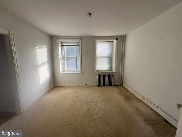 spare room featuring radiator heating unit and light colored carpet