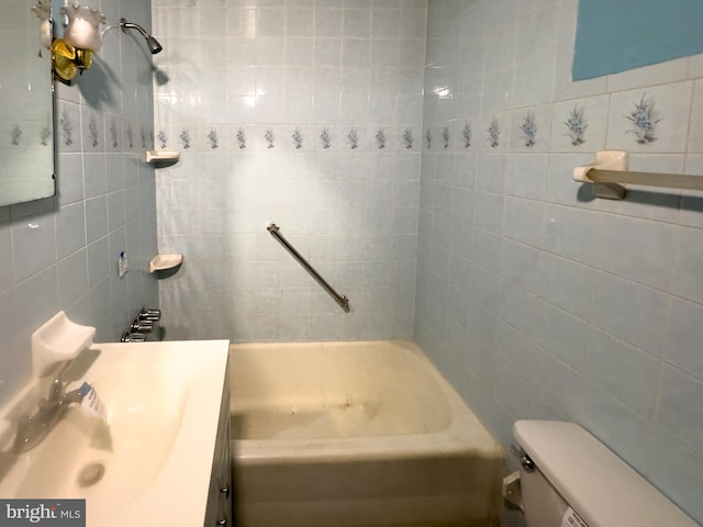 full bathroom with vanity, toilet, tile walls, and tiled shower / bath