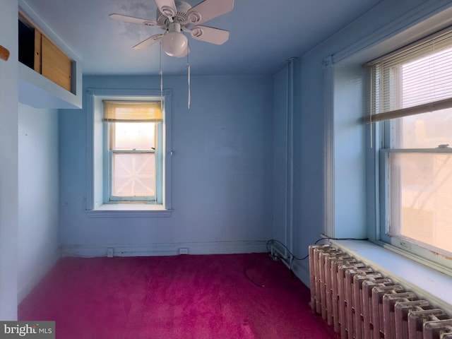 carpeted empty room featuring radiator heating unit, plenty of natural light, and ceiling fan