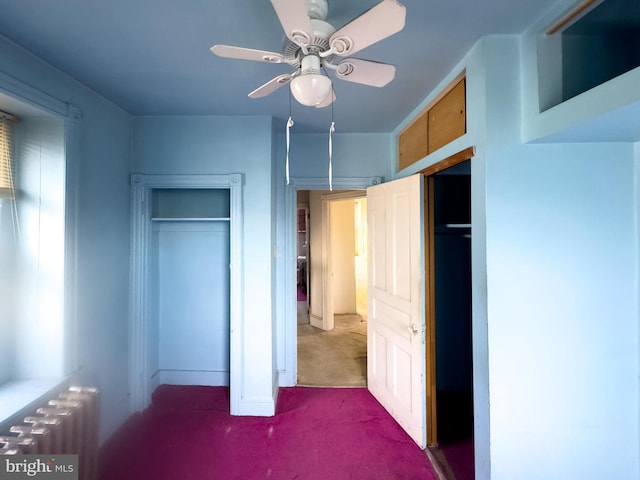 unfurnished bedroom featuring carpet flooring, ceiling fan, and radiator heating unit