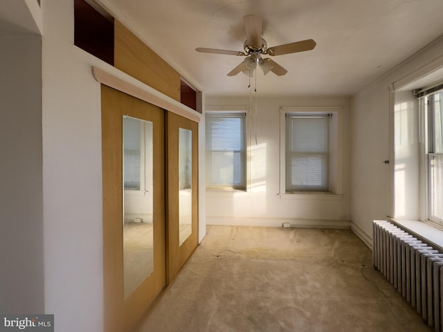 unfurnished room with light carpet, radiator, french doors, ceiling fan, and a wealth of natural light