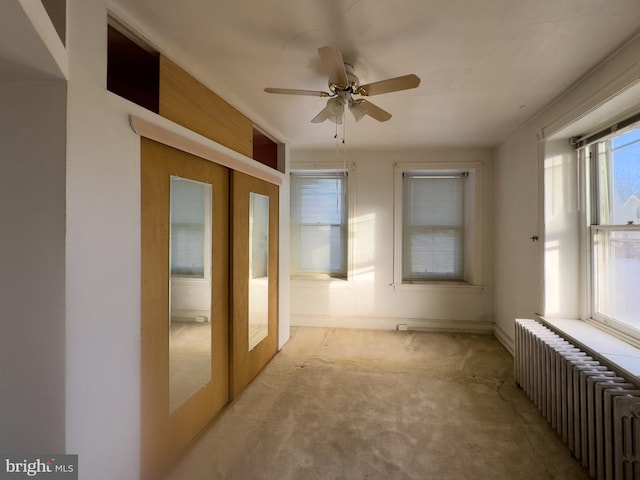 spare room featuring radiator heating unit, light colored carpet, french doors, and ceiling fan