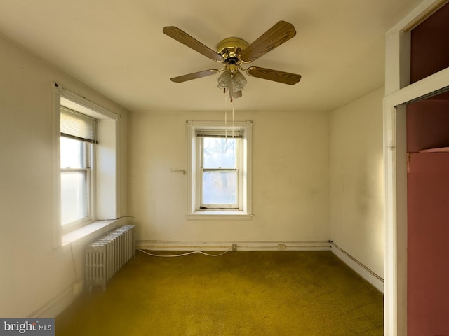 carpeted spare room featuring ceiling fan and radiator heating unit