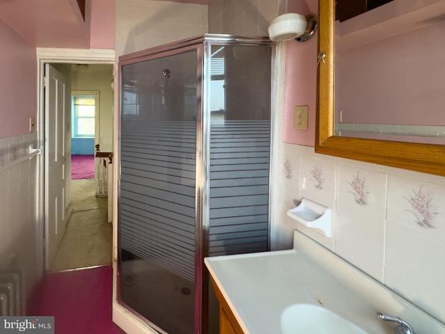 bathroom featuring vanity, a shower with door, and tasteful backsplash