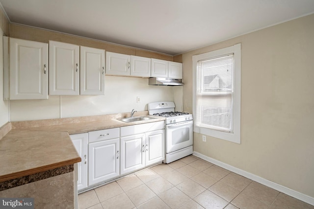 kitchen with white gas range, sink, white cabinets, and light tile patterned flooring