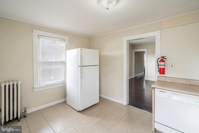 kitchen with white cabinets, white appliances, radiator, and light tile patterned floors