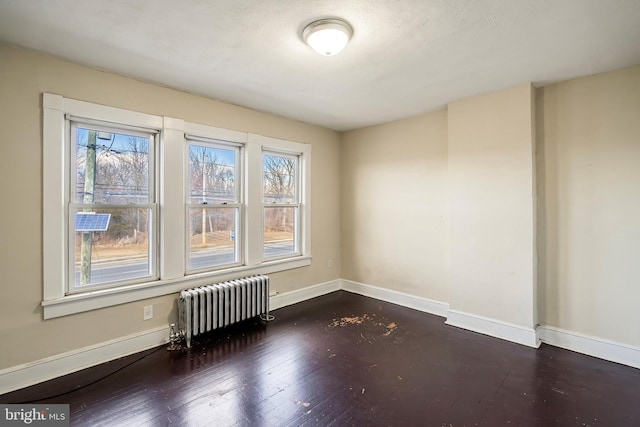 empty room featuring radiator and dark wood-type flooring