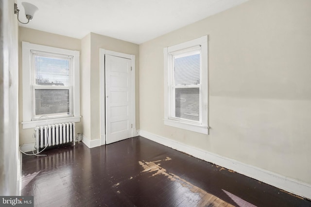 unfurnished room featuring radiator and dark hardwood / wood-style floors