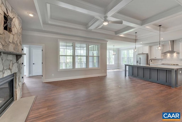 unfurnished living room with sink, coffered ceiling, crown molding, a fireplace, and ceiling fan with notable chandelier