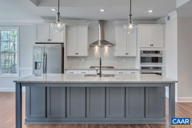 kitchen featuring appliances with stainless steel finishes, a kitchen island with sink, and wall chimney range hood