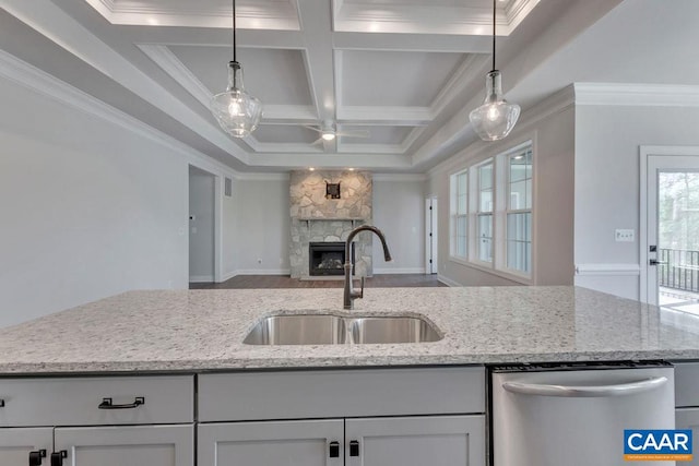 kitchen with stainless steel dishwasher, decorative light fixtures, light stone countertops, and sink