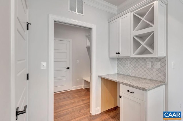 kitchen with white cabinets, light stone countertops, crown molding, and tasteful backsplash