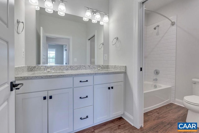 full bathroom with vanity, tiled shower / bath combo, hardwood / wood-style flooring, and toilet