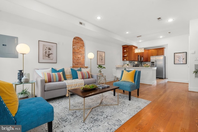 living room with electric panel and light hardwood / wood-style flooring