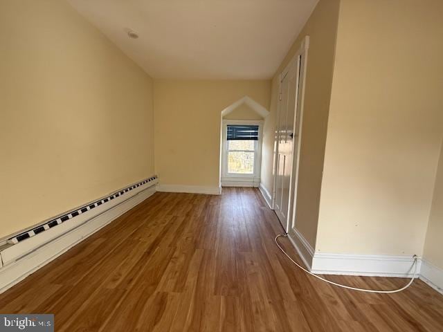 bonus room with hardwood / wood-style flooring and a baseboard heating unit