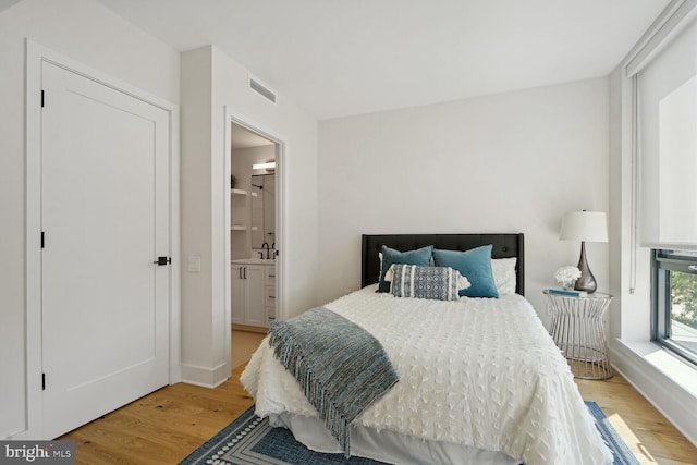 bedroom featuring ensuite bath and light hardwood / wood-style floors