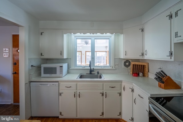 kitchen featuring hardwood / wood-style floors, white appliances, white cabinets, sink, and decorative backsplash