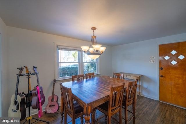 dining area with dark wood-type flooring and an inviting chandelier