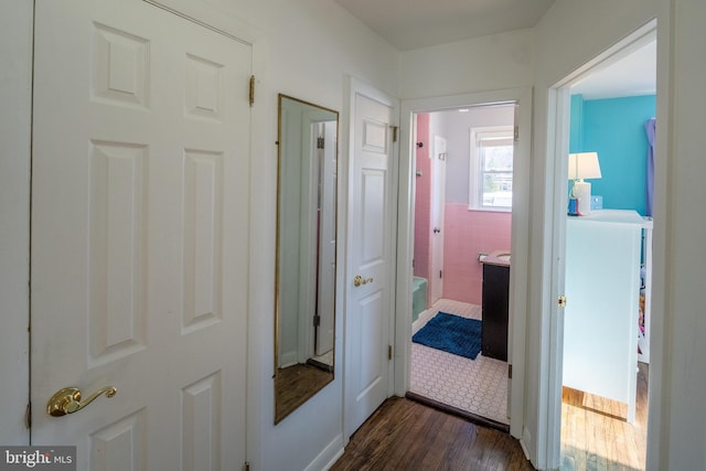 hall featuring dark wood-type flooring and tile walls