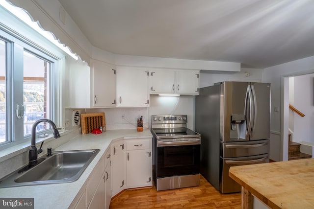 kitchen featuring sink, white cabinetry, stainless steel appliances, and light wood-type flooring