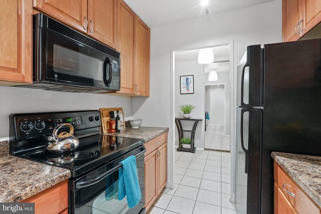 kitchen featuring black appliances, light tile patterned flooring, and stone counters