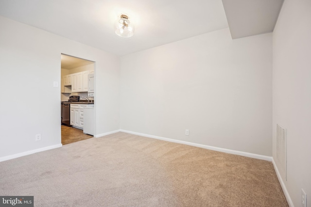 spare room featuring light carpet and sink