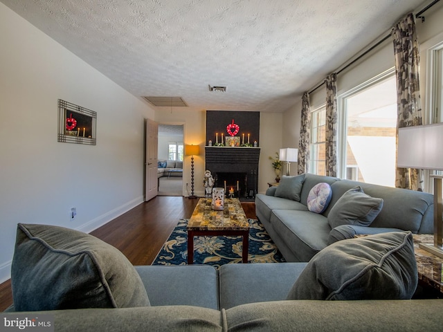 living room with a textured ceiling and dark hardwood / wood-style flooring