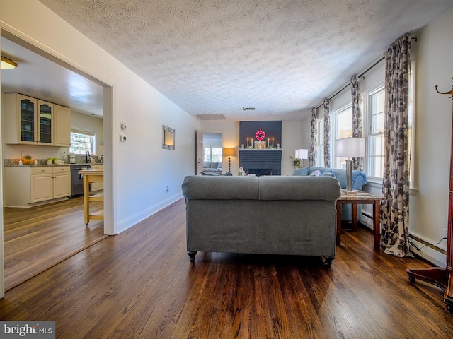 living room featuring a textured ceiling, a healthy amount of sunlight, and dark hardwood / wood-style floors