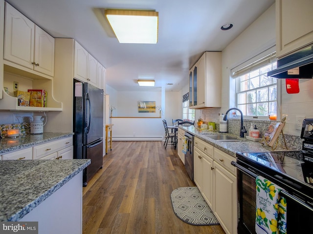 kitchen with sink, white cabinets, wood-type flooring, a baseboard heating unit, and black appliances