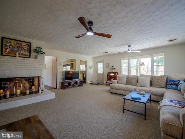 living room featuring a fireplace, a textured ceiling, carpet, ceiling fan, and baseboard heating