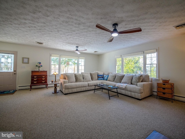 carpeted living room with ceiling fan, a textured ceiling, baseboard heating, and a healthy amount of sunlight