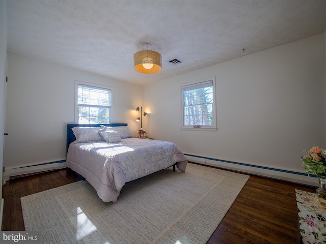 bedroom featuring dark hardwood / wood-style flooring, a baseboard heating unit, and a textured ceiling