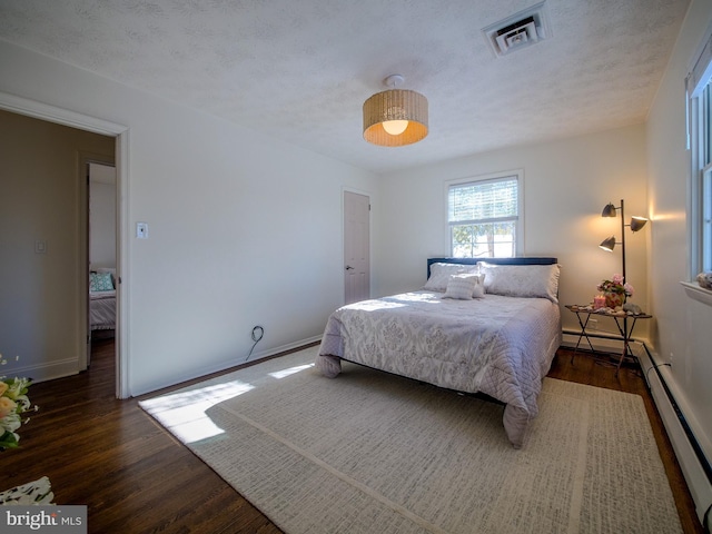 bedroom featuring a textured ceiling, dark wood-type flooring, and a baseboard radiator