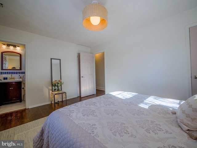 bedroom with ensuite bath and dark hardwood / wood-style floors