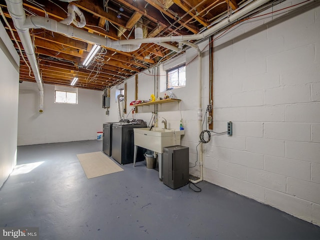 basement with a healthy amount of sunlight, washing machine and dryer, and sink