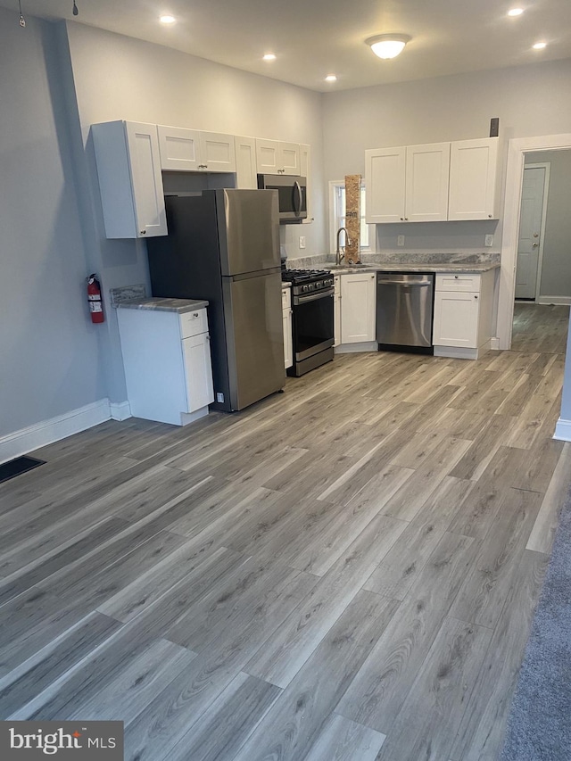 kitchen featuring white cabinets, light hardwood / wood-style floors, sink, and appliances with stainless steel finishes