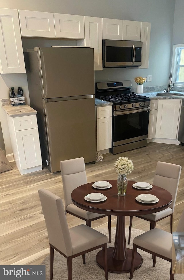 kitchen featuring white cabinetry, sink, stainless steel appliances, and light hardwood / wood-style flooring