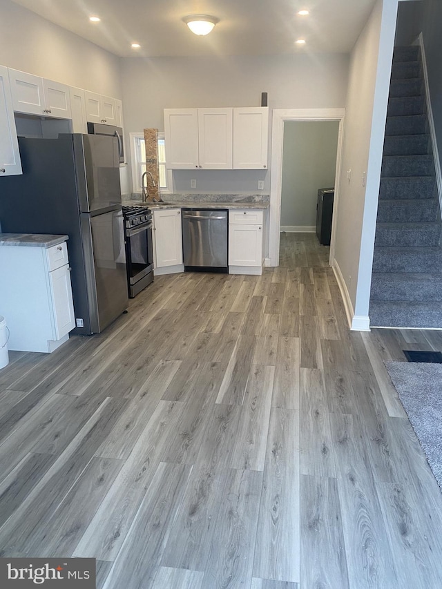 kitchen featuring sink, white cabinets, stainless steel appliances, and light wood-type flooring