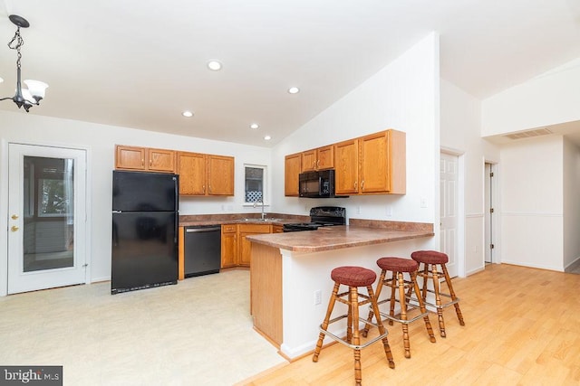 kitchen featuring sink, hanging light fixtures, a kitchen breakfast bar, kitchen peninsula, and black appliances