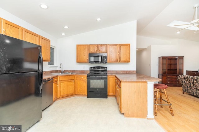 kitchen with lofted ceiling, sink, a kitchen breakfast bar, black appliances, and kitchen peninsula