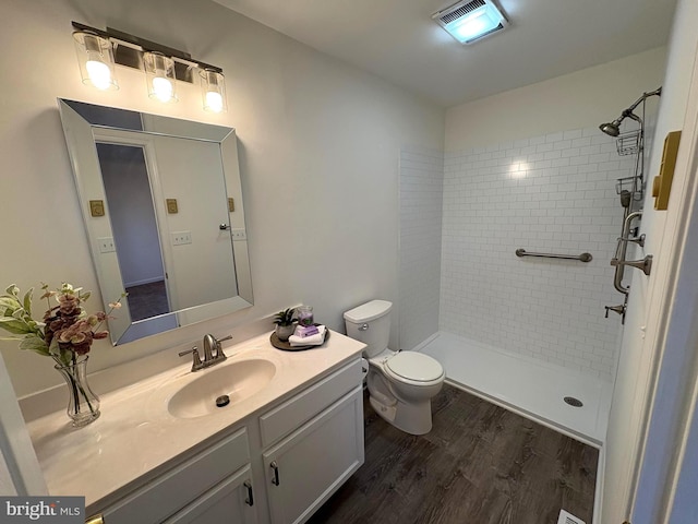 bathroom featuring tiled shower, vanity, toilet, and hardwood / wood-style floors