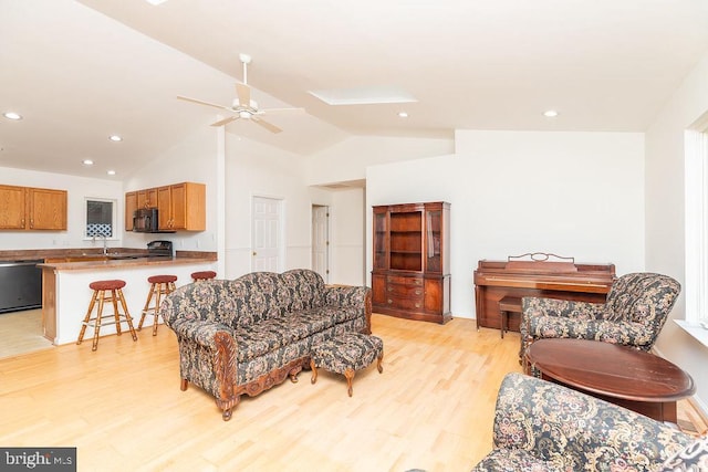 living room featuring ceiling fan, lofted ceiling, sink, and light hardwood / wood-style flooring