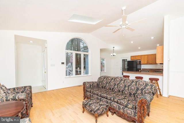 living room with light hardwood / wood-style flooring, ceiling fan, and vaulted ceiling