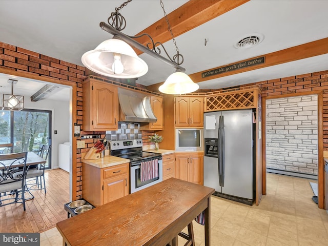 kitchen with decorative light fixtures, brick wall, extractor fan, and appliances with stainless steel finishes