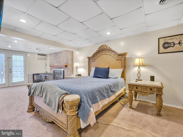 carpeted bedroom featuring an AC wall unit, access to exterior, french doors, and a brick fireplace