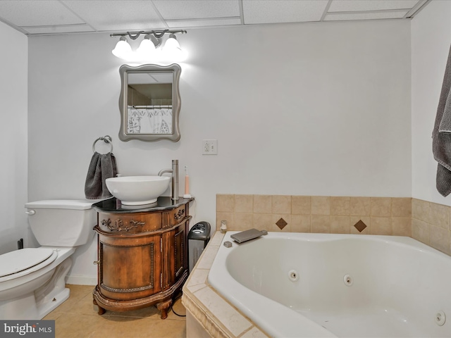 bathroom featuring a paneled ceiling, vanity, a relaxing tiled tub, tile patterned flooring, and toilet