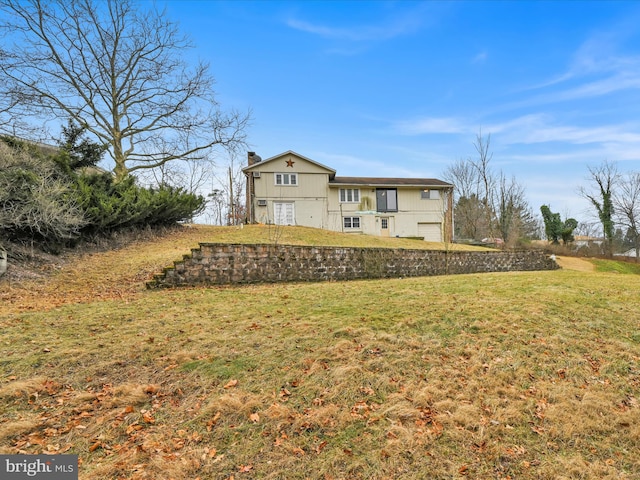 rear view of house with a garage and a lawn