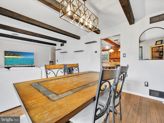 dining area with beam ceiling, hardwood / wood-style flooring, and a notable chandelier