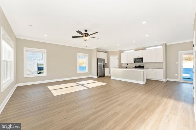 unfurnished living room featuring crown molding, sink, light hardwood / wood-style flooring, and a wealth of natural light