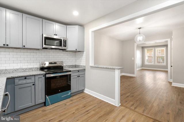 kitchen featuring pendant lighting, gray cabinetry, backsplash, and appliances with stainless steel finishes